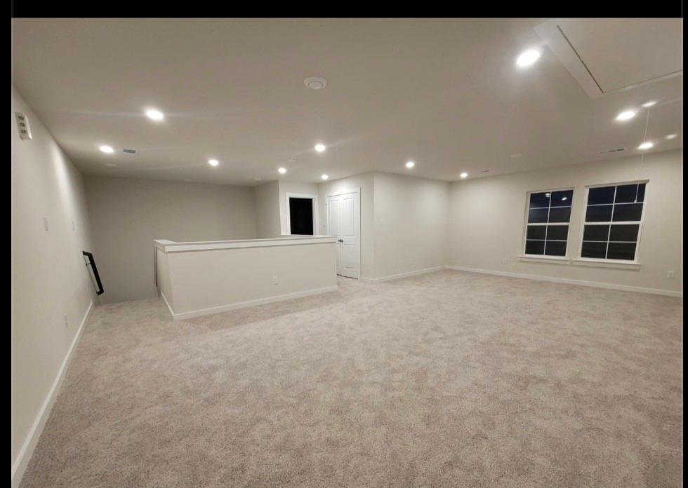 785 Vineyard Way Forney, TX 75126 - Photo 10 of 12 Spacious carpeted room featuring recessed lighting, two double-hung windows with grid patterns, and a half-wall partition