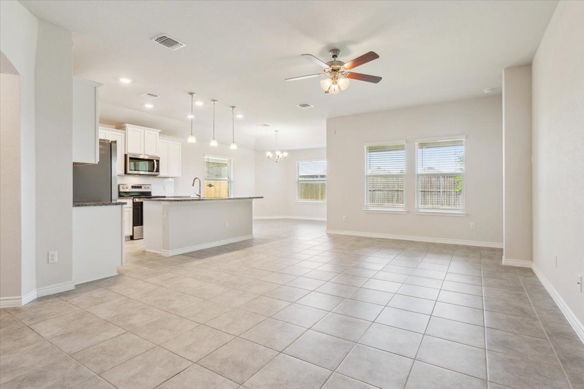 5830 Copano Road Belton, TX 76513 - Photo 11 of 34 Unfurnished living room featuring light tile patterned floors, baseboards, arched walkways, a sink, and ceiling fan with notable chandelier