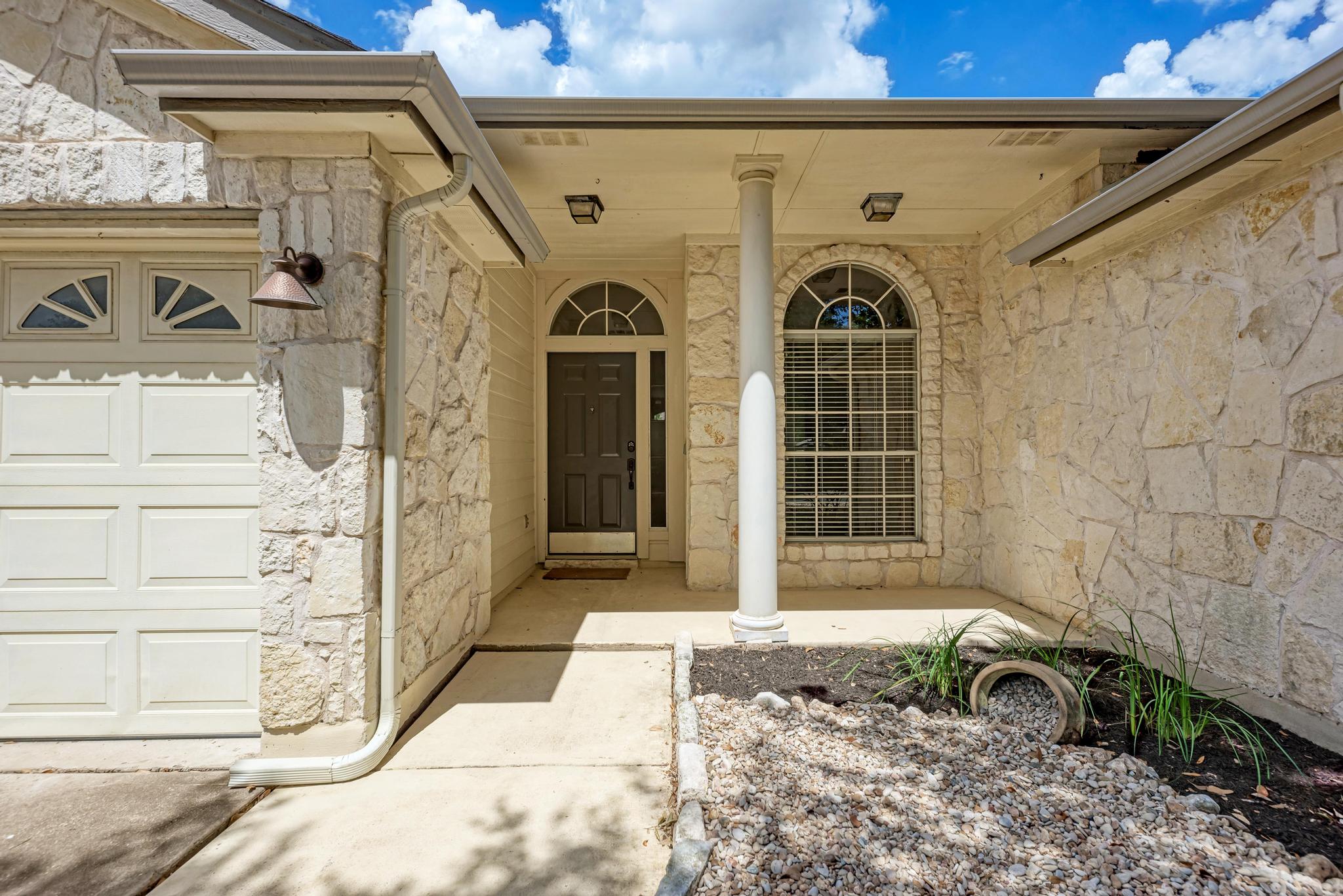 4408 Tello Path Austin, TX 78749 - Photo 2 of 38 Doorway to property featuring stone siding, a garage, and covered porch