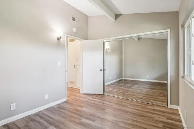 a view of an empty room with wooden floor and a bathroom