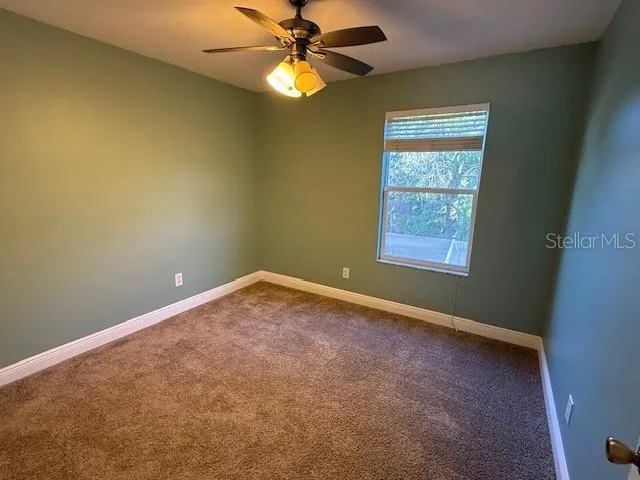 an empty room with a window and a fan