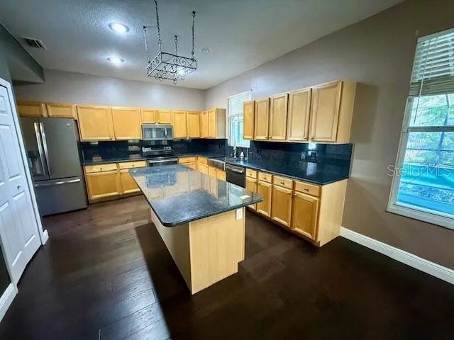 a kitchen with stainless steel appliances granite countertop a sink a stove counter space and a window