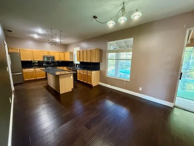 an open kitchen with wooden floor and stainless steel appliances