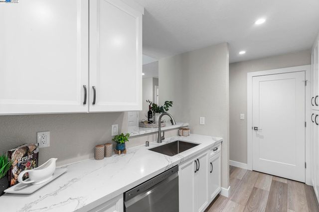 a kitchen with stainless steel appliances white cabinets a sink and wooden floor