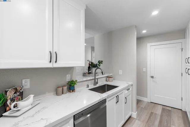 a kitchen with stainless steel appliances white cabinets a sink and wooden floor
