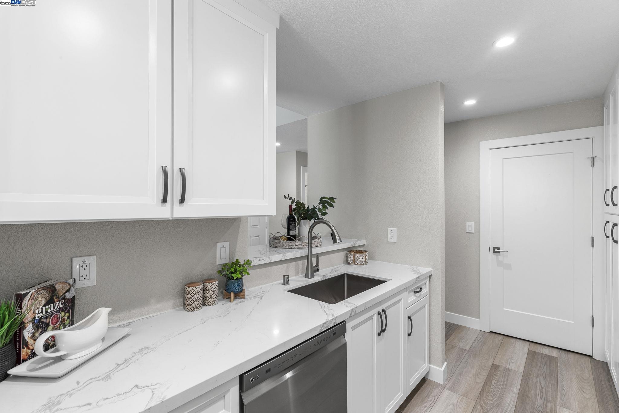 8170 Mountain View Drive, Unit F Pleasanton, CA 94588 - Photo 20 of 51 a kitchen with stainless steel appliances white cabinets a sink and wooden floor