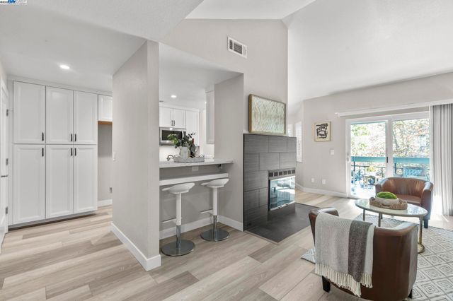 a living room with furniture a flat screen tv and a refrigerator