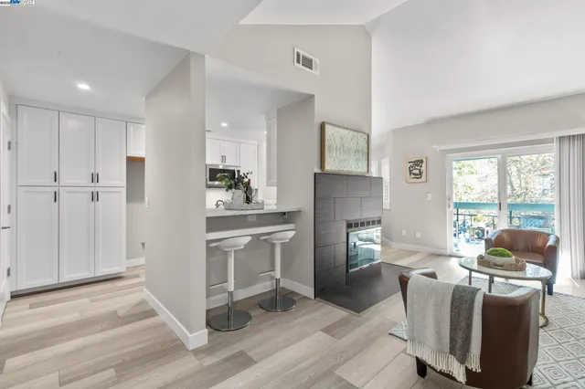 a living room with furniture a flat screen tv and a refrigerator