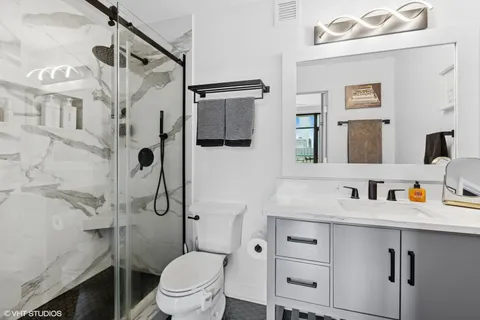 a bathroom with a sink toilet vanity and shower