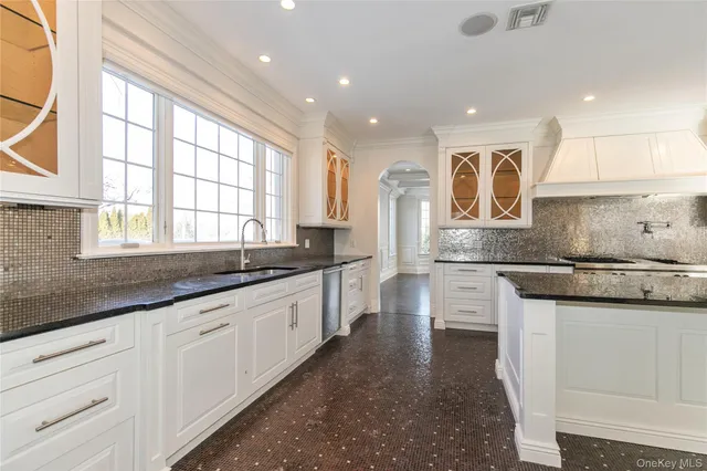 a large kitchen with granite countertop a large window and white cabinets