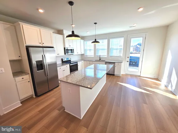 a large kitchen with stainless steel appliances granite countertop a refrigerator a sink dishwasher a stove and white countertops with wooden floor