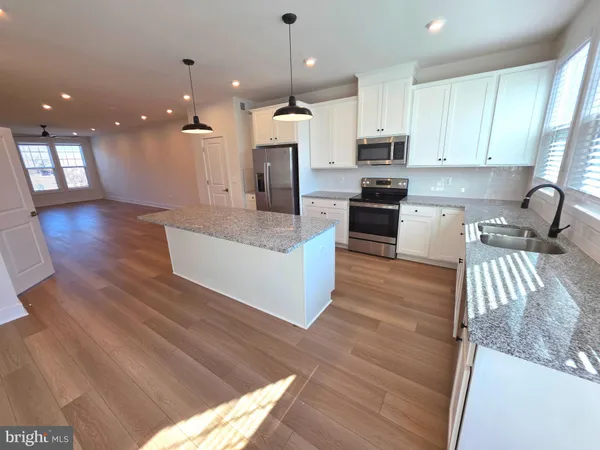 a large kitchen with stainless steel appliances kitchen island granite countertop a stove a refrigerator a sink and a dining table with wooden floor