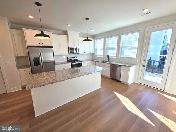 a large kitchen with kitchen island a large counter top space a sink stainless steel appliances and cabinets