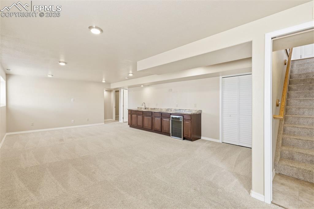 11515 Texarkanna Road Peyton, CO 80831 - Photo 36 of 49 Finished basement featuring bar with sink, light colored carpet, and wine cooler