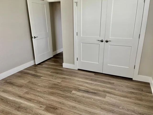a view of an empty room with closet and wooden floor