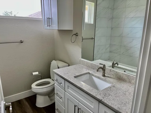 a bathroom with a granite countertop sink a toilet and a mirror