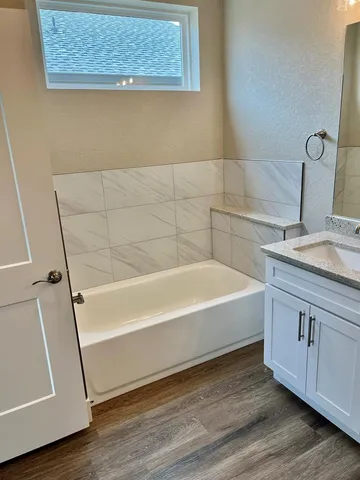 a bathroom with a granite countertop sink and a bathtub