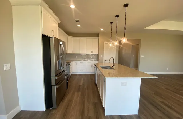 a kitchen with stainless steel appliances granite countertop a refrigerator a sink and a stove