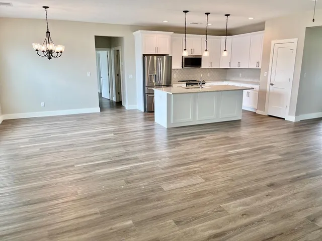 a kitchen with stainless steel appliances granite countertop a refrigerator a stove and a wooden floors