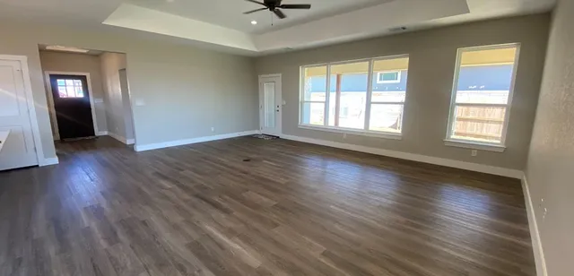 an empty room with wooden floor and windows