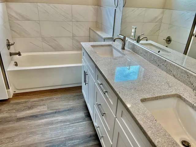 a bathroom with a granite countertop bathtub sink and mirror