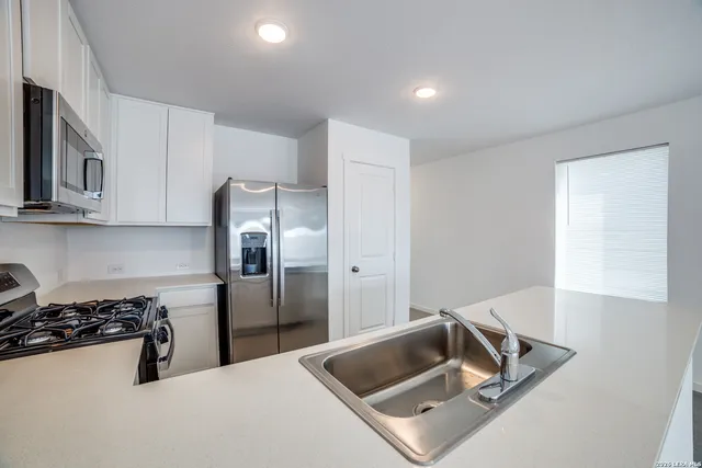 a kitchen with stainless steel appliances granite countertop a sink and a refrigerator