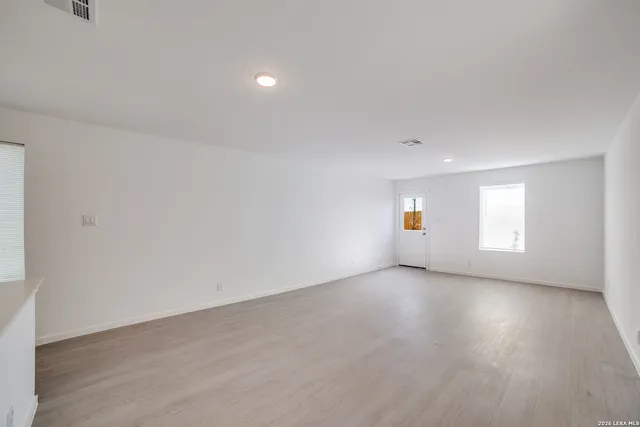 an empty room with wooden floor and windows