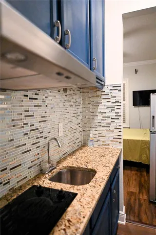 a kitchen sink with granite countertop white cabinets and a sink