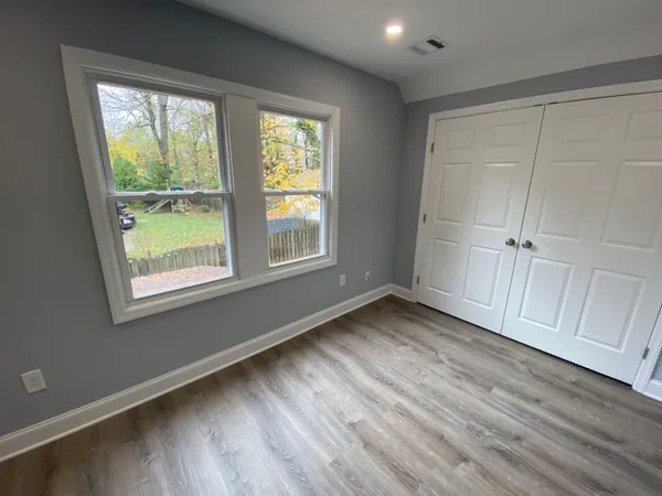 an empty room with wooden floor and windows