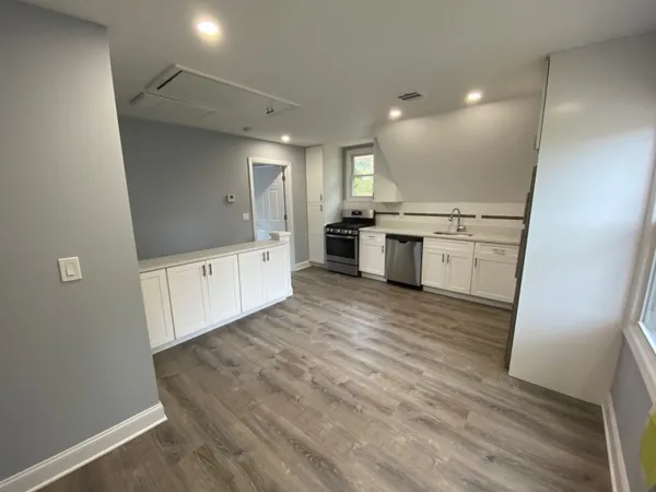 a large room with kitchen island a sink wooden floor and glass door