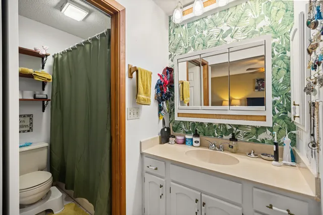 a bathroom with a granite countertop sink toilet and shower