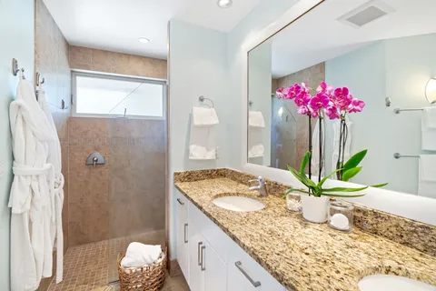 a bathroom with a granite countertop sink a large mirror and a shower