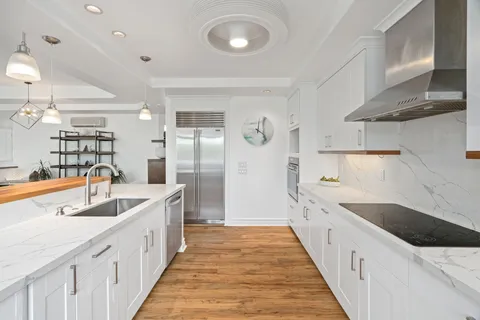 a large white kitchen with a sink and refrigerator