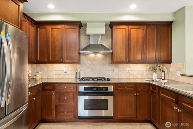 a kitchen with stainless steel appliances granite countertop a sink a stove and a wooden cabinets