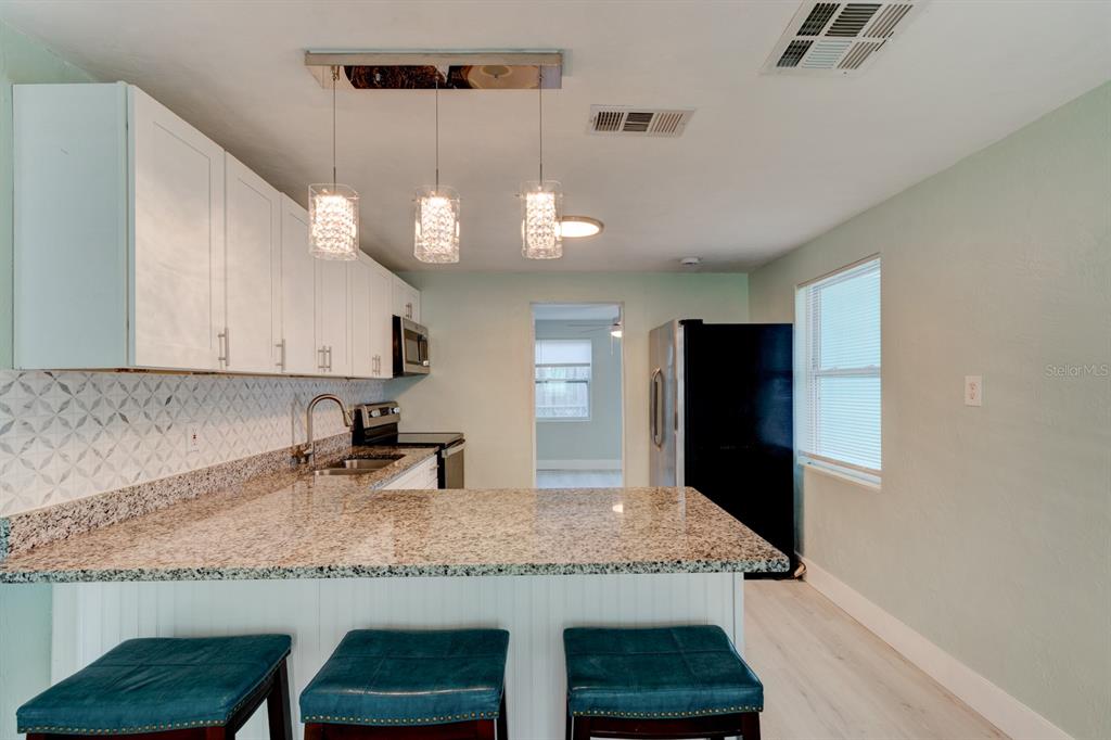 404 Adele Street Edgewater, FL 32132 - Photo 5 of 23 a kitchen with granite countertop kitchen island stainless steel appliances a sink and a refrigerator