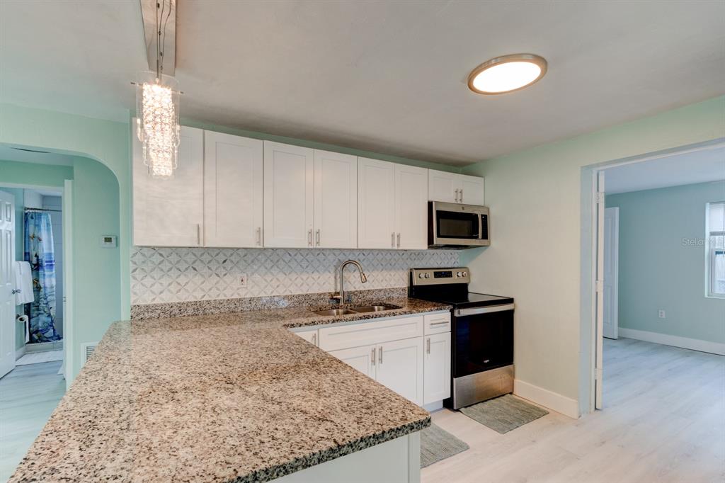 404 Adele Street Edgewater, FL 32132 - Photo 6 of 23 a kitchen with granite countertop a sink and a stove top oven
