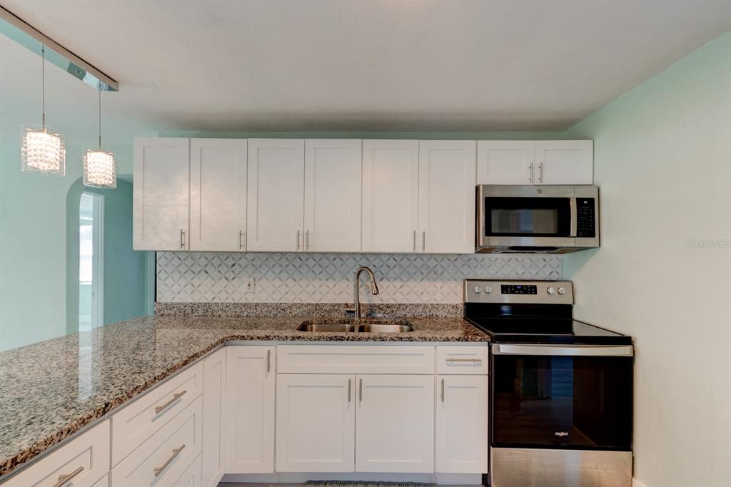 404 Adele Street Edgewater, FL 32132 - Photo 7 of 23 a kitchen with granite countertop white cabinets and stainless steel appliances