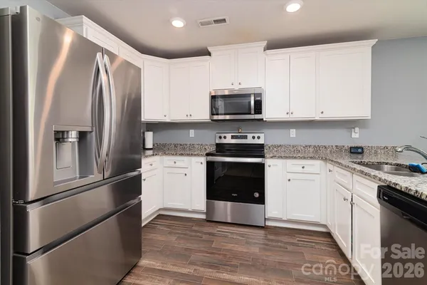 a kitchen with stainless steel appliances granite countertop a refrigerator stove and sink