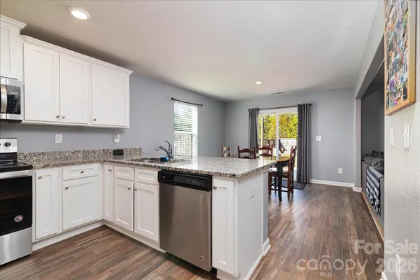 a kitchen with granite countertop cabinets stainless steel appliances a sink and a window