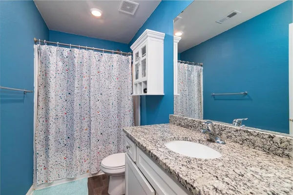 a bathroom with a granite countertop sink toilet and shower
