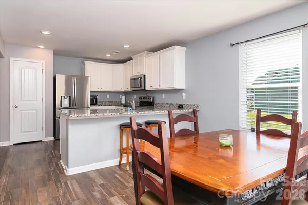 a kitchen with stainless steel appliances granite countertop a stove top oven a sink dishwasher and a refrigerator with wooden floor