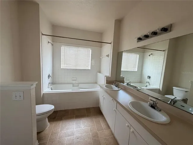 a bathroom with a granite countertop sink toilet tub and mirror