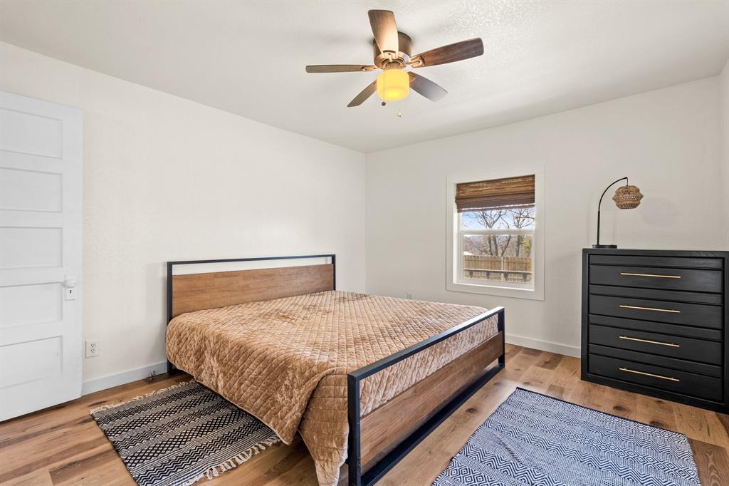 1550 South Stewart Street Azle, TX 76020 - Photo 32 of 35 a bedroom with a bed and a ceiling fan with a bookshelf
