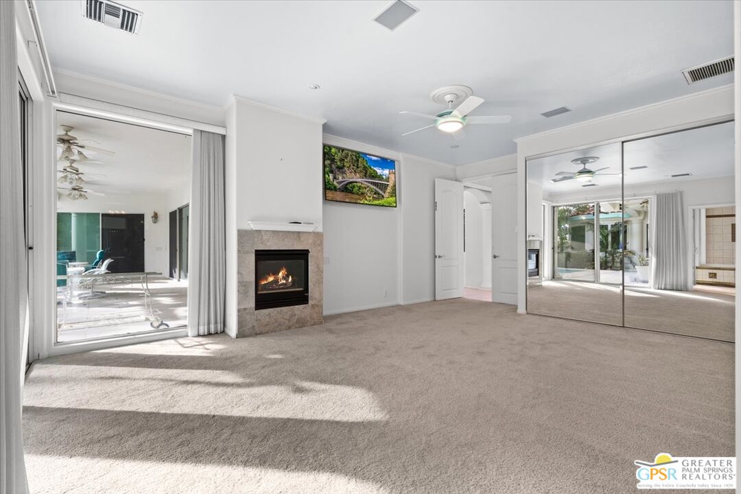 875 Tamarisk Road Palm Springs, CA 92262 - Photo 27 of 55 a view of a livingroom with a fireplace a ceiling fan and windows