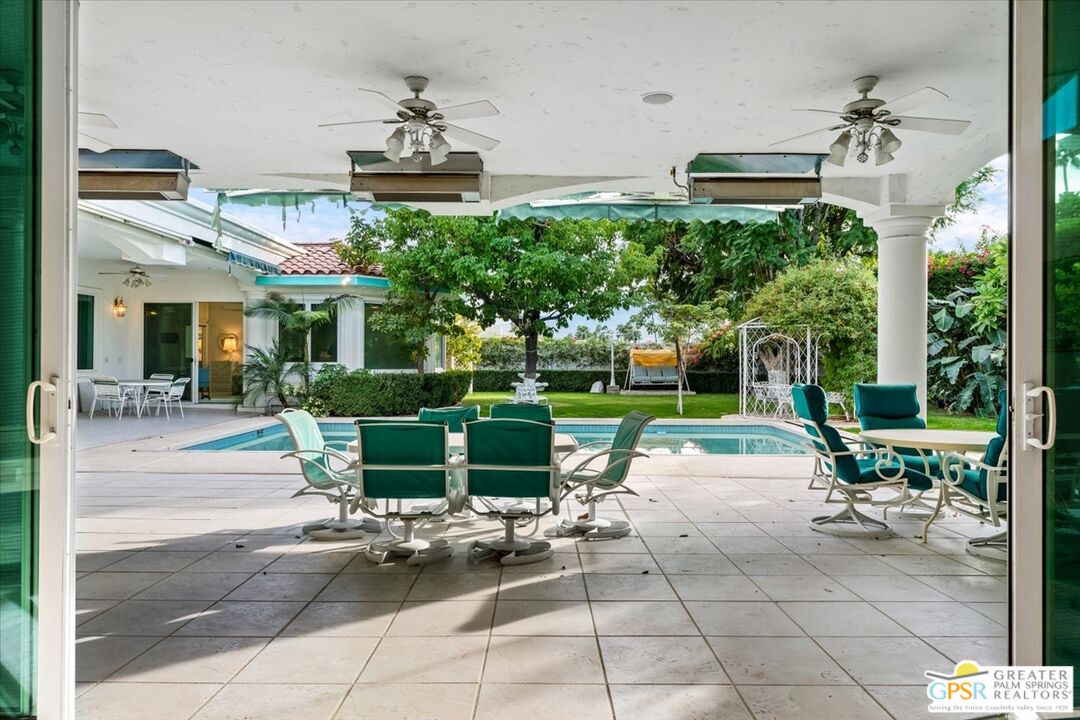 875 Tamarisk Road Palm Springs, CA 92262 - Photo 46 of 55 a view of a patio with table and chairs potted plants and a large tree