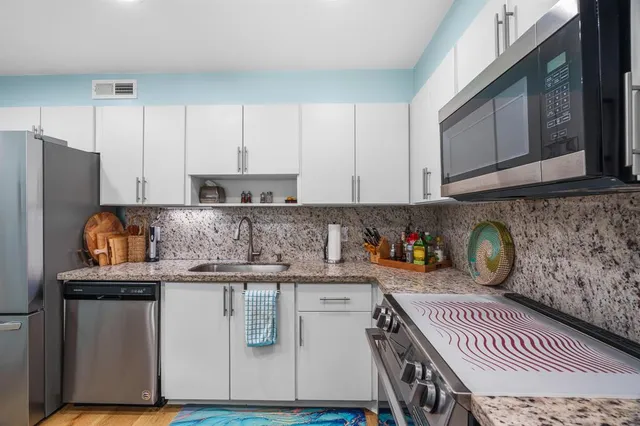 a kitchen with stainless steel appliances granite countertop a stove a sink and a refrigerator