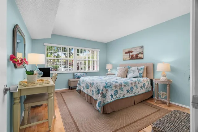 a bedroom with a bed table chair and a window