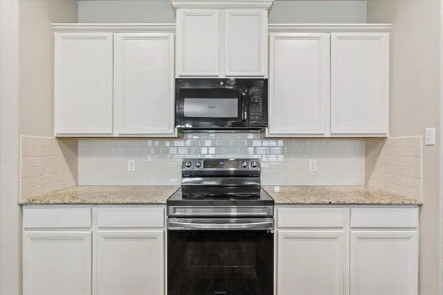 a kitchen with granite countertop white cabinets and a stove top oven