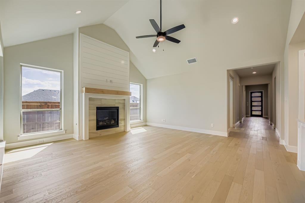 1809 Flowerfield Lane Mansfield, TX 76063 - Photo 6 of 29 Unfurnished living room featuring light wood finished floors, high vaulted ceiling, a tile fireplace, recessed lighting, and a ceiling fan