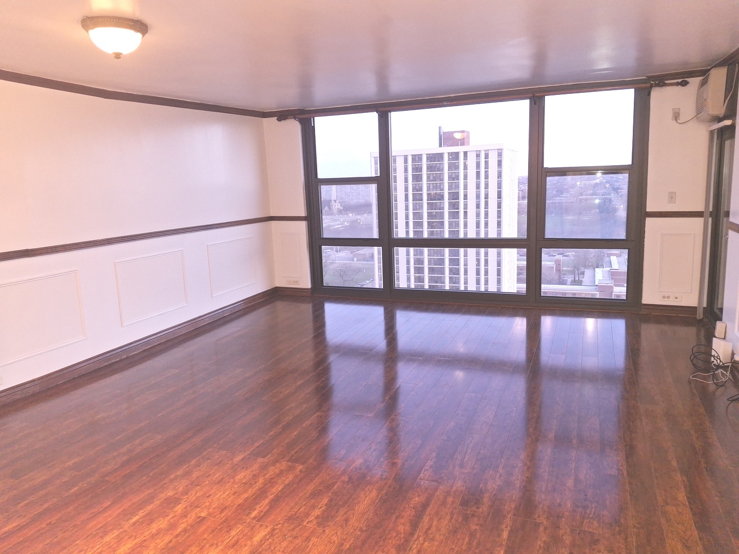 2605 South Indiana Avenue, Unit 1909 Chicago, IL 60616 - Photo 2 of 19 a view of an empty room with wooden floor and a window